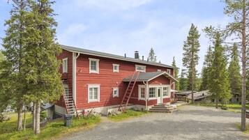 A red wooden house with a porch, a ladder, and a bicycle.