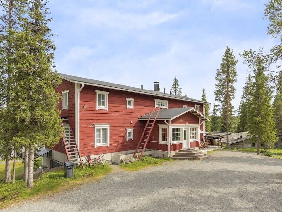 A red wooden house with a porch, a ladder, and a bicycle.