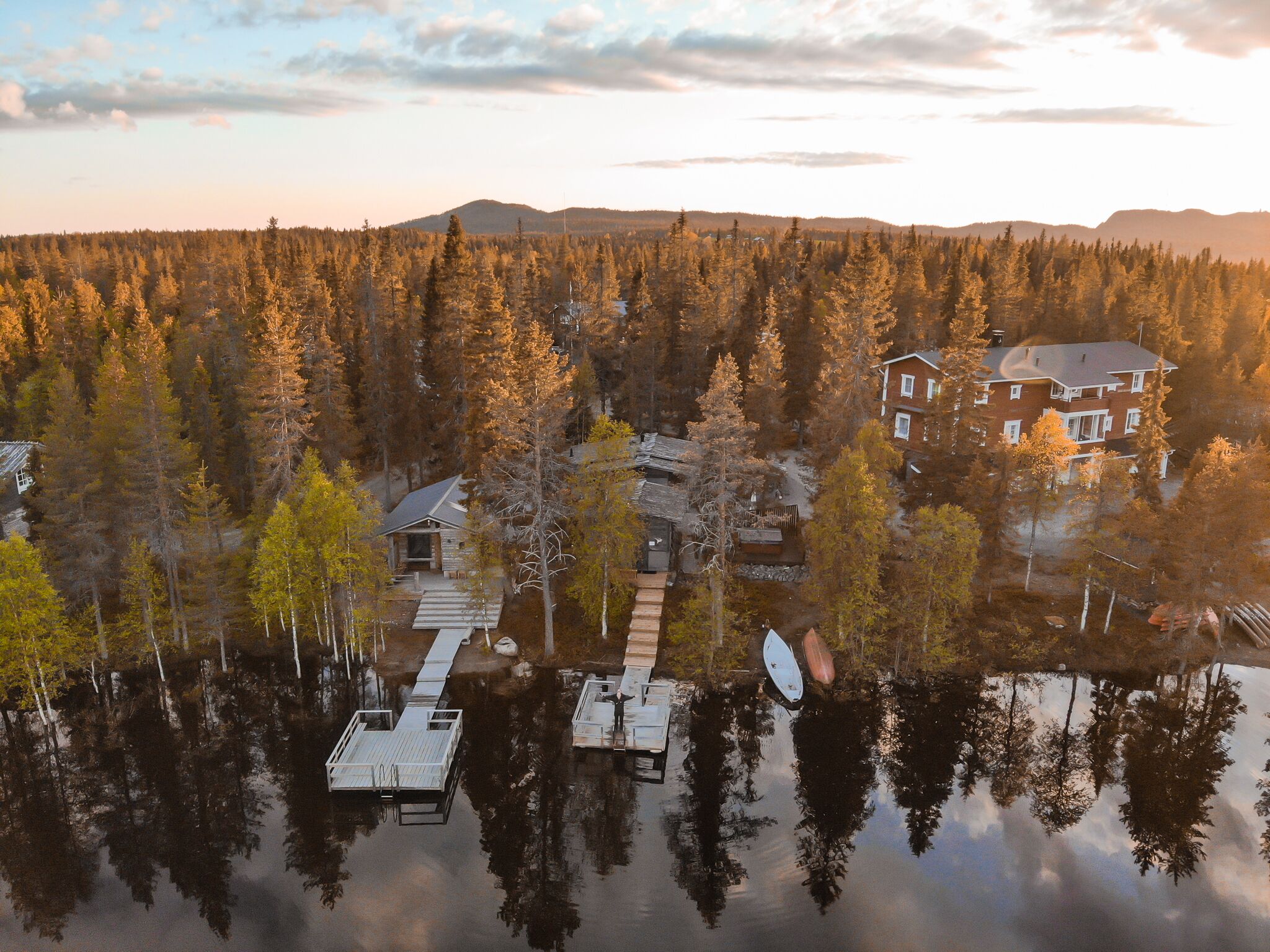 A lakeside property with a main house, a smaller cabin, and a dock extending into the water.