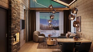 A modern living room with a stone fireplace, comfortable seating, a wooden dining table, and a large window with a view of a snowy landscape.