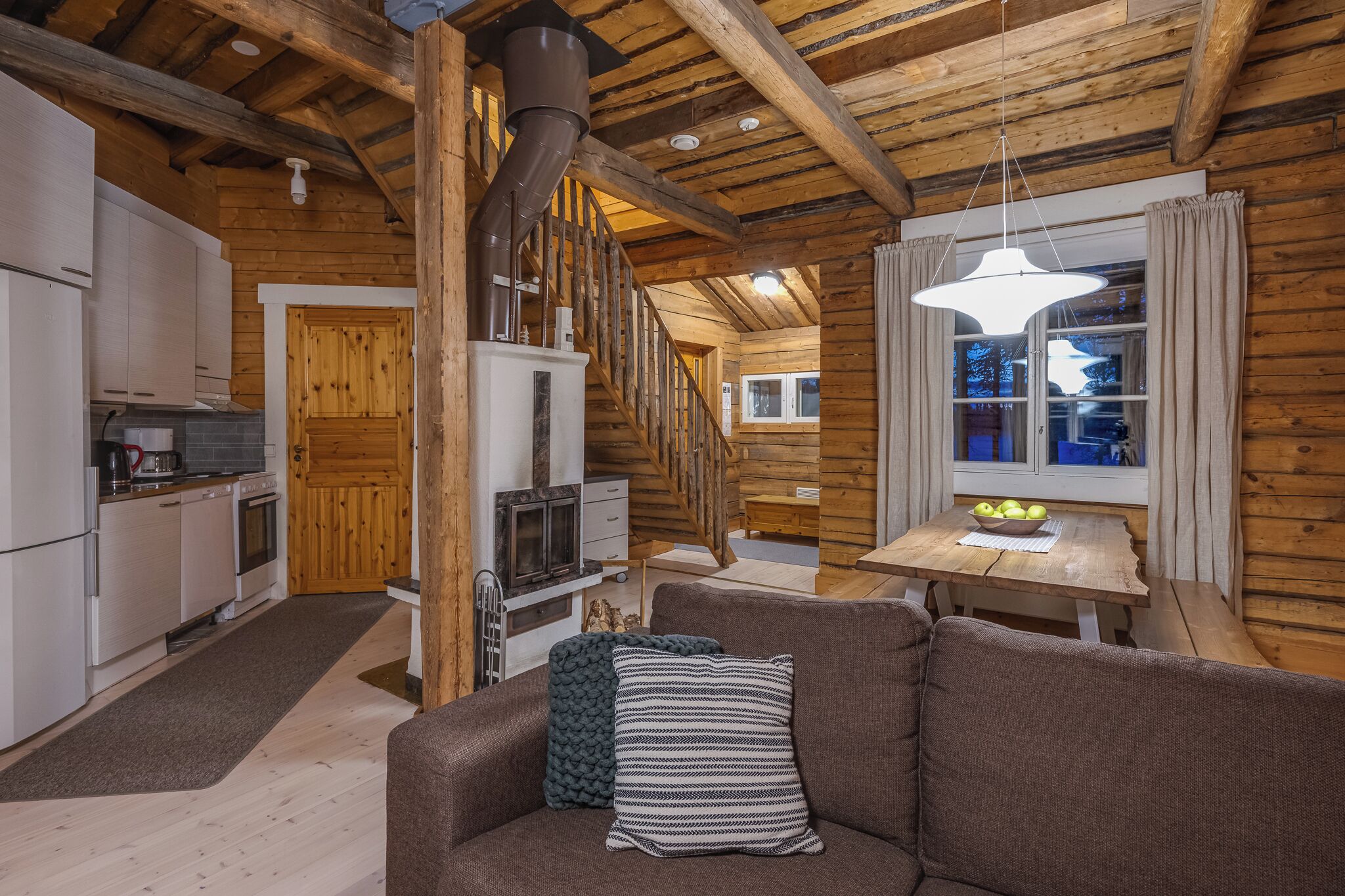 Ein gemütliches Blockhaus-Interieur mit Küche, Essbereich und einer Treppe.