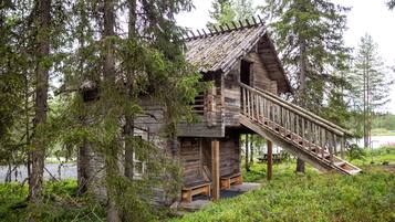 Un rustico chalet con una scala di legno che conduce a un portico, immerso in una fitta foresta.
