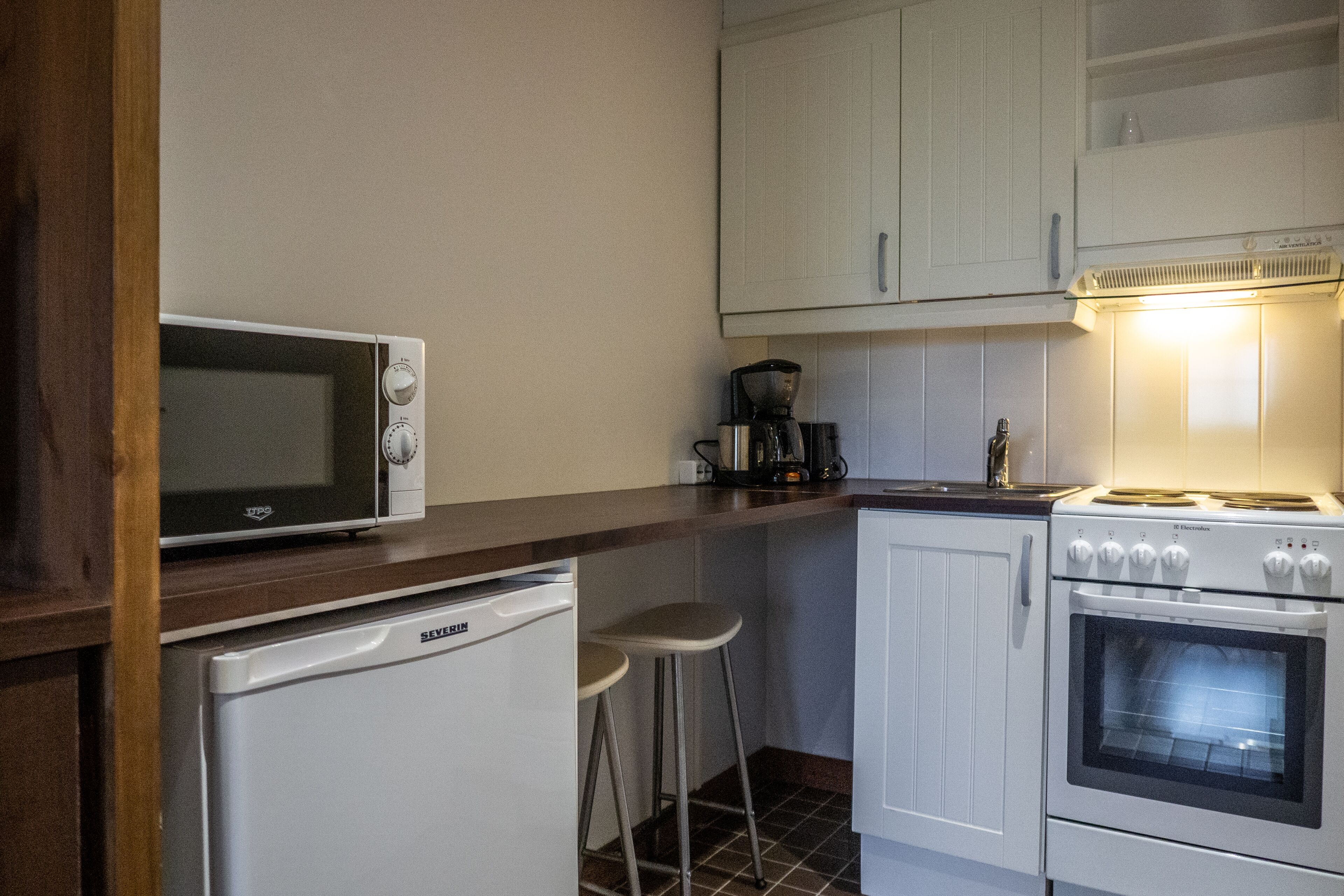 A compact kitchen with a microwave, a small refrigerator, a coffee maker, and an oven.