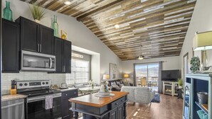 A modern kitchen with dark cabinets, a stainless steel stove, and a large island. - 2BR Condo | Near SDC & Table Rock Lake (Branson)