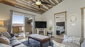 A spacious living room with a fireplace, a television, and a large window overlooking a scenic view. - 2BR Condo | Near SDC & Table Rock Lake (Branson)