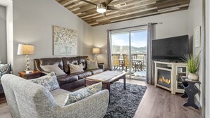 A living room with a leather couch, a coffee table, a fireplace, and a TV. - 2BR Condo | Near SDC & Table Rock Lake (Branson)