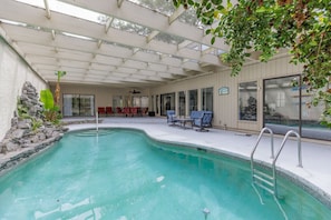 Una piscina interior con un patio cubierto, paredes de piedra y asientos.