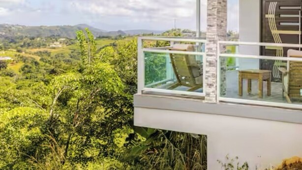 A modern building with a balcony overlooking a lush landscape. - Charming house, stunning views in brilliant Barranquitas with AC, WiFi, Parking (Barranquitas)