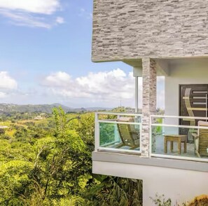 A modern building with a balcony overlooking a lush landscape.