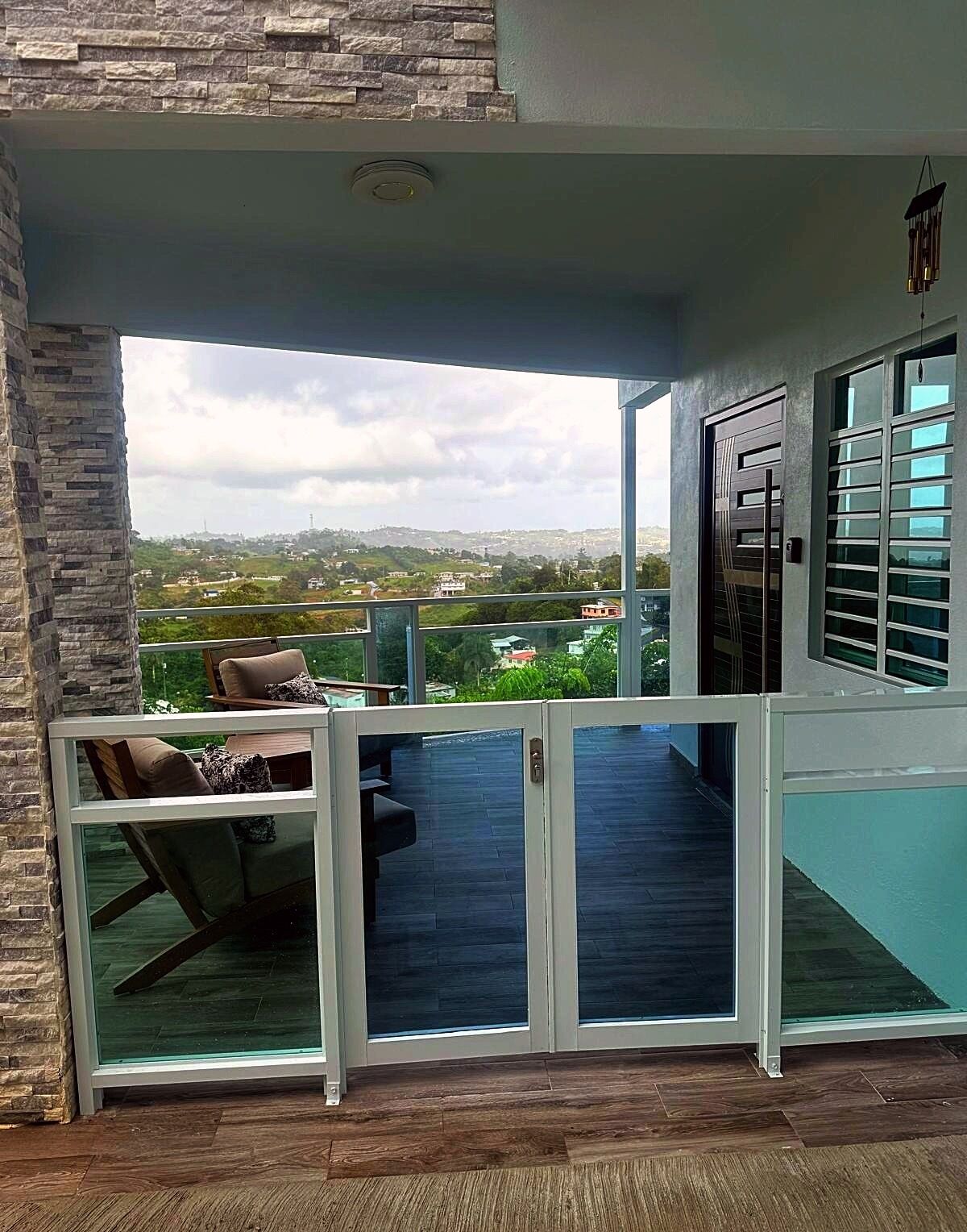 Un balcone con un muro in pietra, una porta vetrata e vista sulla città.