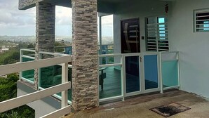 A modern building with a stone facade, large windows, and a balcony with a white railing. - Charming house, stunning views in brilliant Barranquitas with AC, WiFi, Parking (Barranquitas)