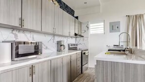 A modern kitchen with marble countertops, stainless steel appliances, and wooden cabinets. - Charming house, stunning views in brilliant Barranquitas with AC, WiFi, Parking (Barranquitas)