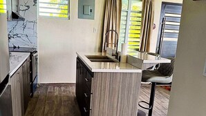A compact kitchen with a central island, a built-in sink, and a small bar area. - Charming house, stunning views in brilliant Barranquitas with AC, WiFi, Parking (Barranquitas)