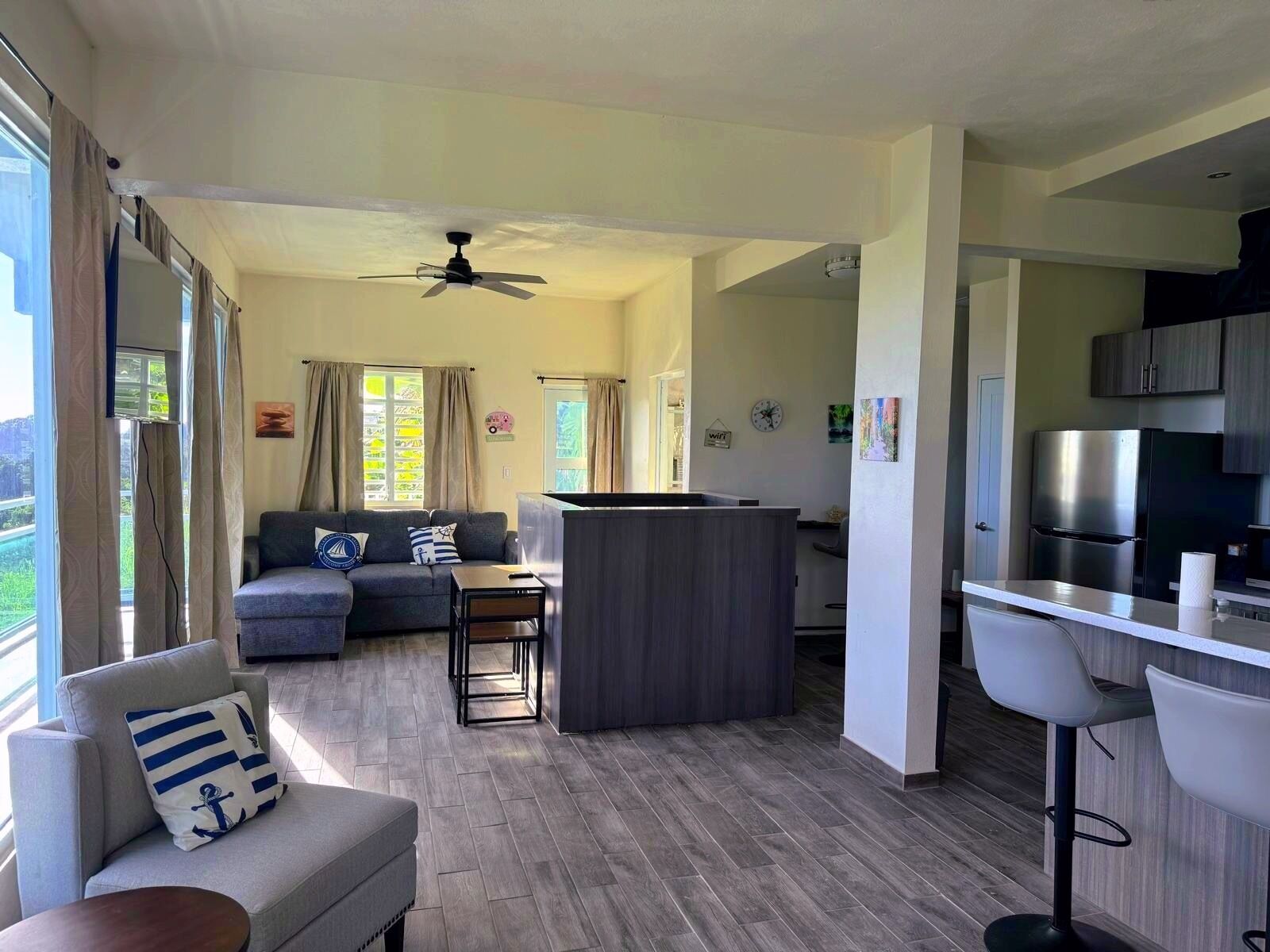 En moderne opholdsstue med sofa, lille bord, barområde og køkken.