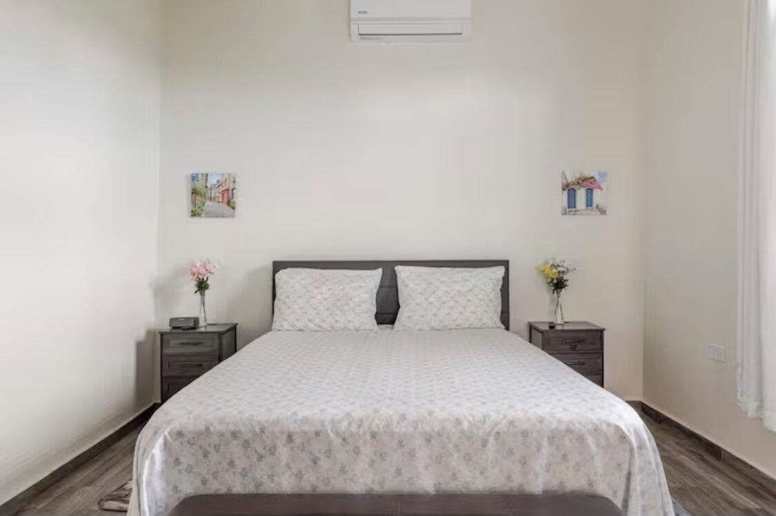 Un dormitorio ordenado con cama, mesitas de noche y adornos en la pared.