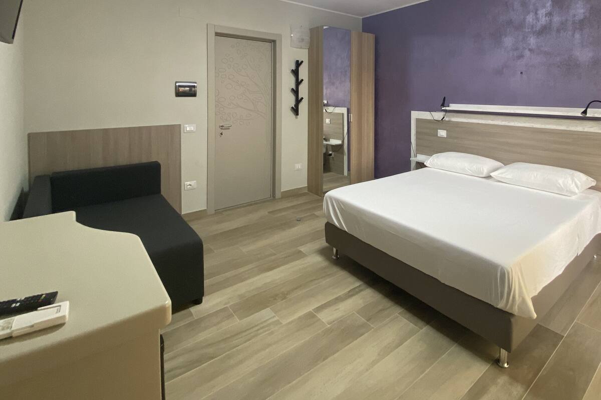 Une chambre d’hôtel avec un lit, un bureau, une chaise et une porte.