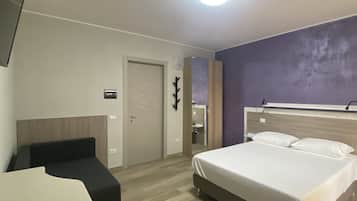 Una habitación de hotel con cama, escritorio, silla y puerta.