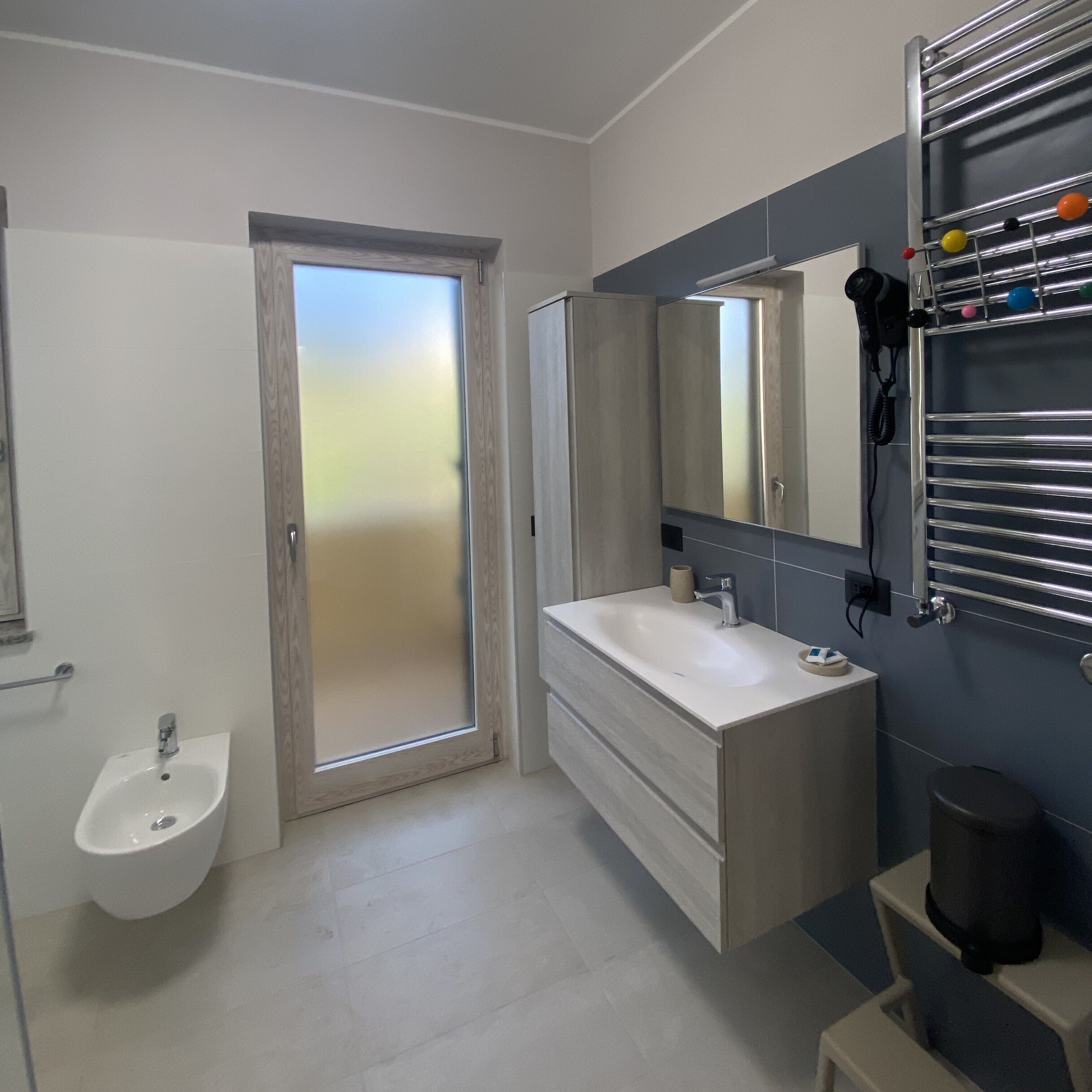 Un baño moderno con lavamanos, espejo y toallero.