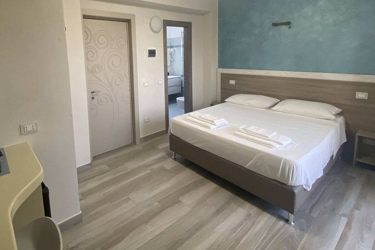 Une chambre à coucher avec un lit, une table de chevet, une chaise et une porte.