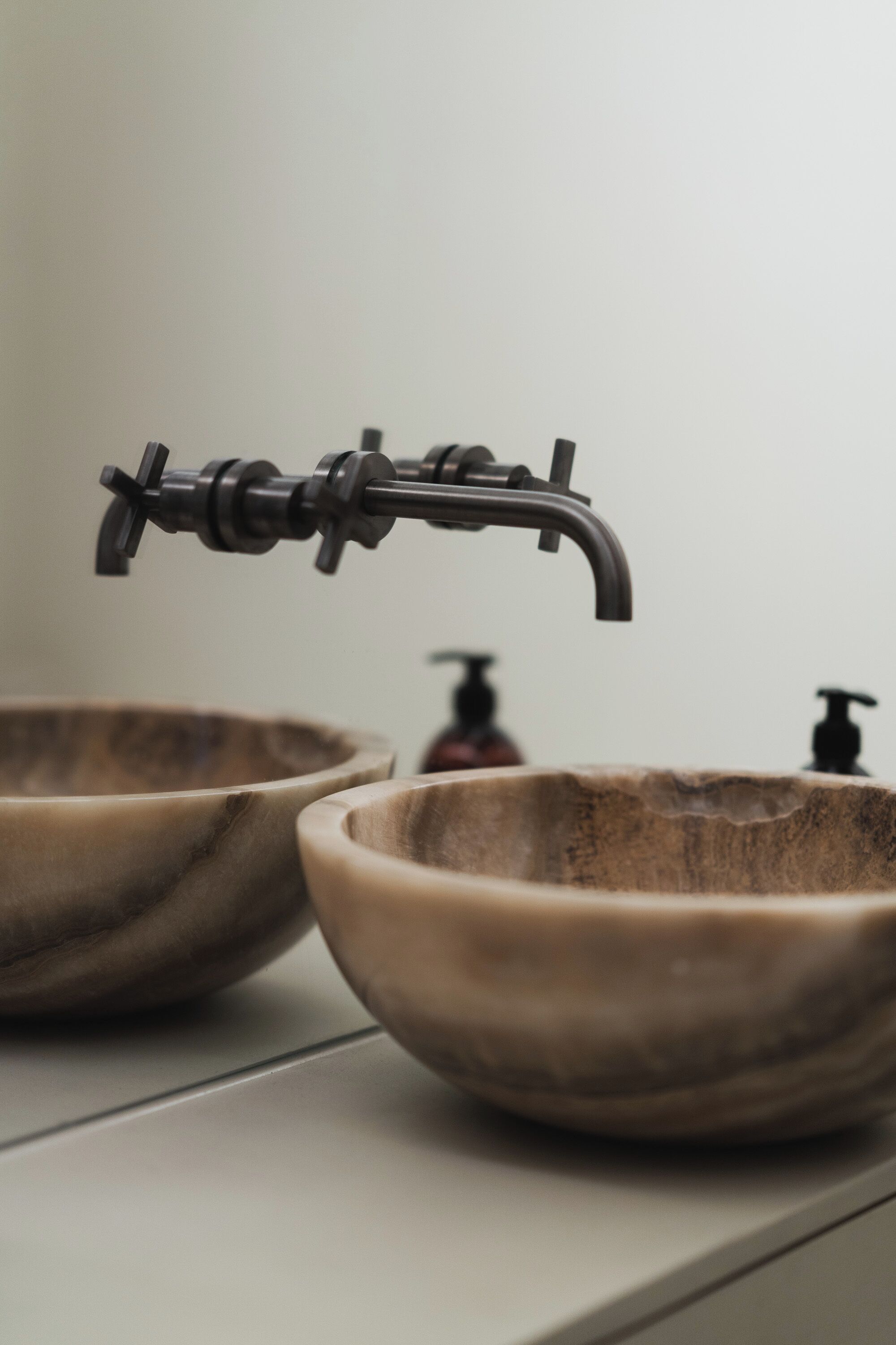 A bathroom with a modern faucet and two wooden bowls on a countertop.