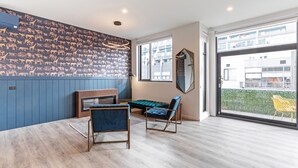 Sala de estar moderna com parede azul, uma janela grande e vista para edifícios.
