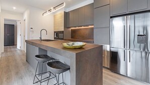 Cozinha moderna com ilha central, eletrodomésticos de aço inoxidável e banquetas.