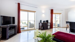 Ein geräumiges Wohnzimmer mit einem Flachbildfernseher, einer dunklen Unterhaltungseinrichtung, einem roten Sofa und einem Blumentopf mit einem Farne.