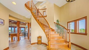 A spacious interior with a wooden staircase, a pool table, and a view of the outdoors. - Soundfront with Private Pool, Hot Tub, Elevator, Private Sound Access, Game Room (Avon)