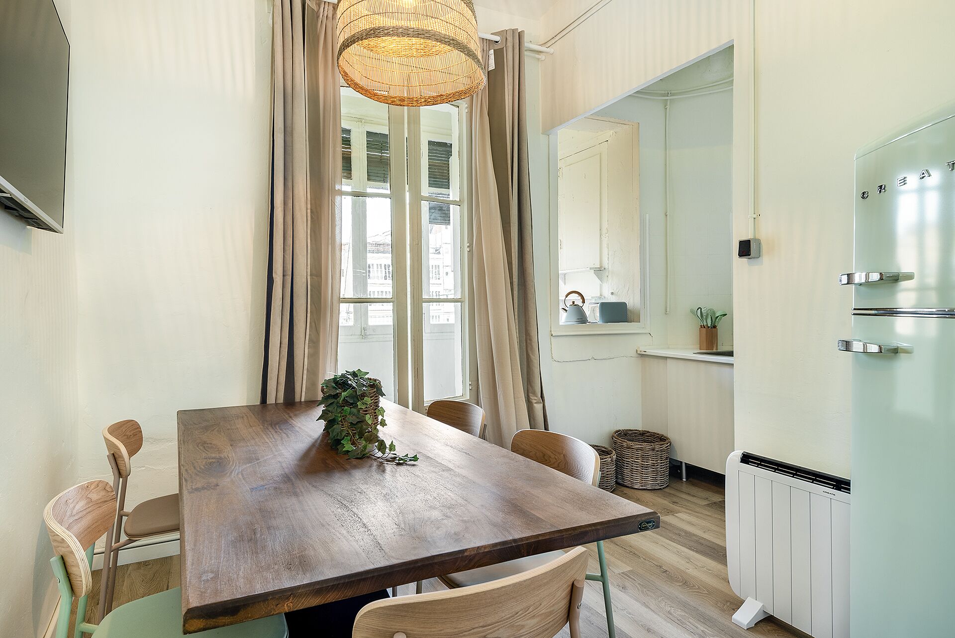 A dining area with a wooden table, chairs, and a hanging light fixture.