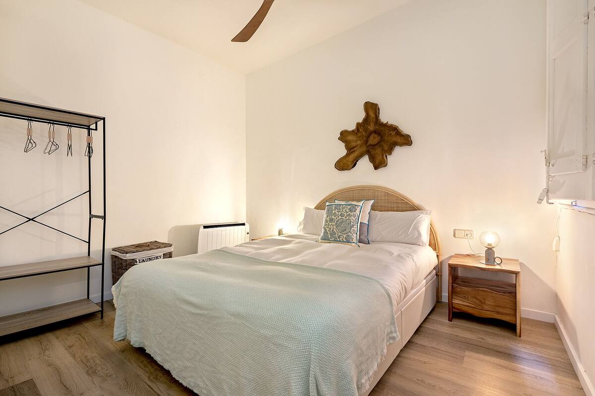 Un dormitorio con cama, mesita de noche, calentador en la pared y suelo de madera.