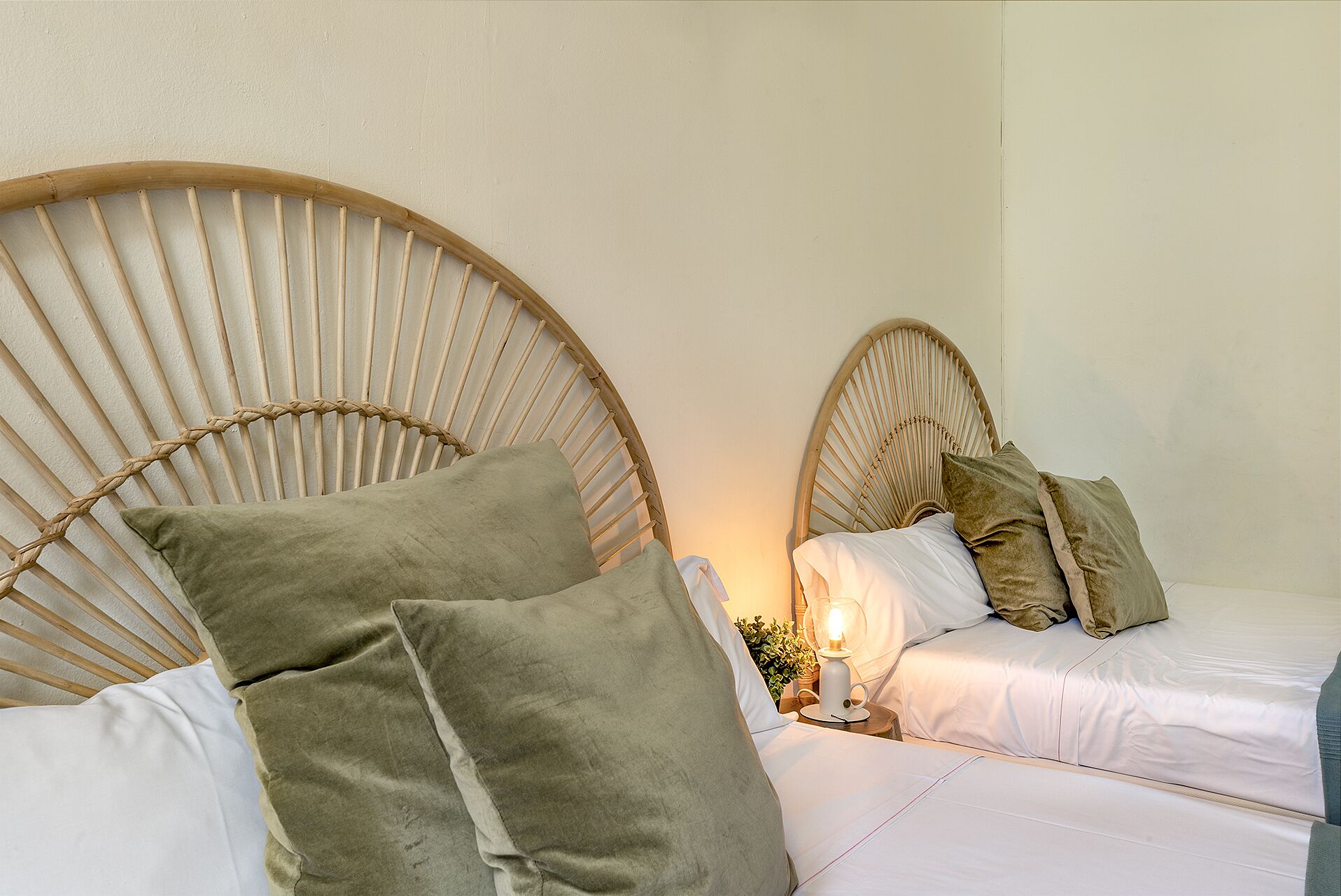 Dos camas con cabeceros de madera, ropa de cama blanca y almohadas verdes.
