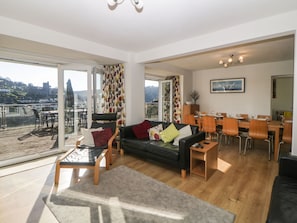 A spacious living area with a balcony, a dining area, and a view of a town.