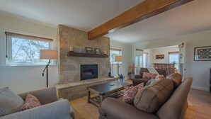 A living room with a stone fireplace, a sofa, a coffee table, and a lamp. - Hilltop Vineyard Estate with 360 Views, Hot Tub & Pool! (Paso Robles)