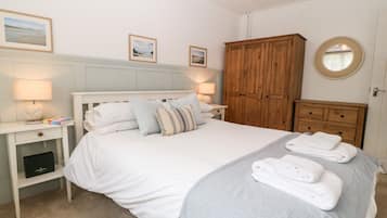 A neatly arranged bedroom with a bed, bedside tables, a wardrobe, and a round mirror.