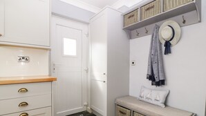 A compact kitchen with white cabinets, a wooden countertop, and a built-in bench with baskets. - Valley Pines (Holyhead)