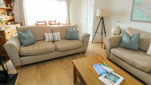 A living room with a sofa, a coffee table with books, a lamp, and a globe. - Valley Pines (Holyhead)