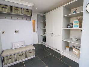 A hallway with a bench, wicker baskets, white cabinets, and shelves with various items. - Valley Pines (Holyhead)