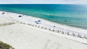 Une plage de sable blanc, avec une eau turquoise et limpide, et quelques parasols.