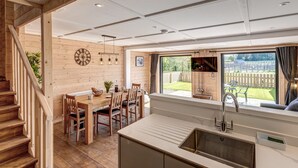 Un interior de madera con comedor, cocina y vistas al exterior.