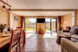 A spacious living area with a wooden floor, a sofa, a coffee table, and a TV in the center.