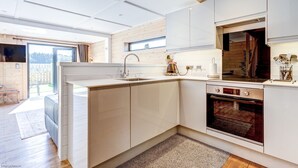 Una cocina moderna con armarios blancos, horno integrado y un amplio ventanal que proporciona luz natural.