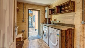 Un interior compacto de madera con lavadora, un banco pequeño y una puerta que da a un espacio al aire libre.