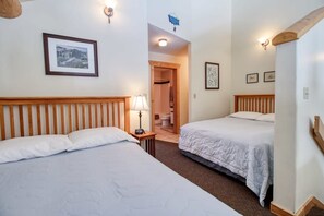 Une chambre d’hôtel avec deux lits, une tête de lit en bois, une table de chevet avec une lampe et un tableau encadré au mur.