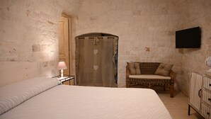 Ein Schlafzimmer mit einem großen Bett, einem Nachttisch mit Lampe, einem Korbstuhl und einem Kleiderschrank.