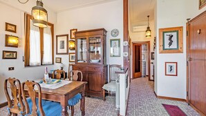 Ein Essbereich mit einem Holztisch, Stühlen und einem Schrank. An den Wänden befinden sich Bilder in Rahmen und eine Chandelieber hängt von der Decke.