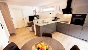 Une cuisine moderne avec des meubles gris, un four encastré et un évier.