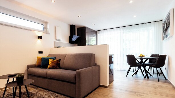 Un salon moderne avec un canapé, une petite table et un coin repas avec des chaises.