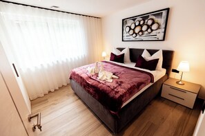 A hotel room with a bed, a nightstand, a lamp, and a painting on the wall.