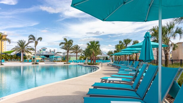 A poolside area with lounge chairs and umbrellas, palm trees, and a building labeled "SALTY RIM." - Relaxing Margaritaville - Townhome (Kissimmee)