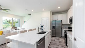 A modern kitchen with white cabinetry, stainless steel appliances, and a large island with a sink. - Relaxing Margaritaville - Townhome (Kissimmee)